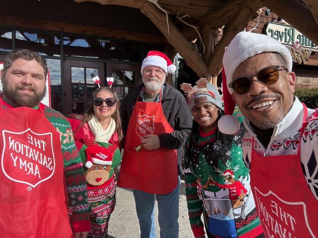 Group of volunteers for The Salvation Army wearing red aprons and santa hats