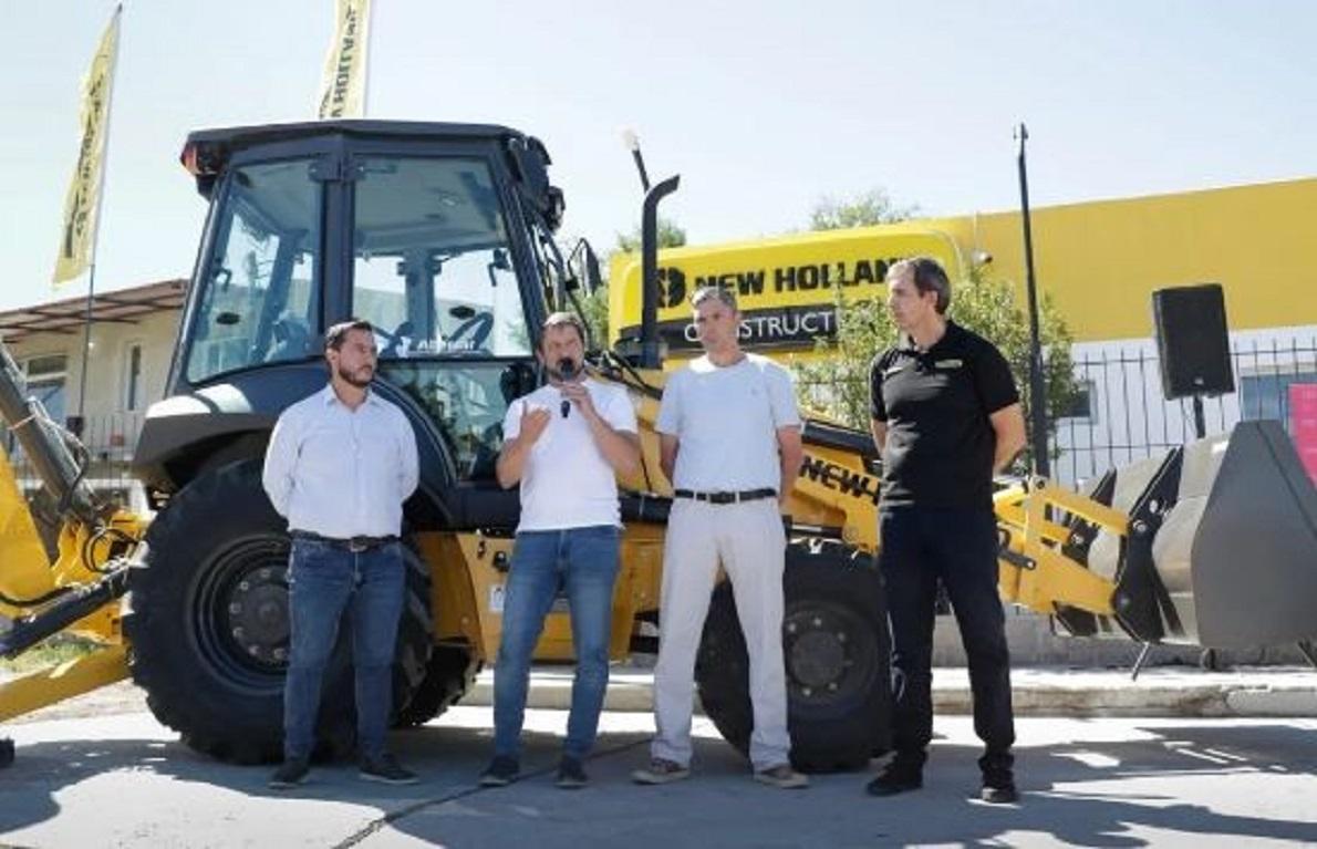 Four people in front of a large construction vehicle.