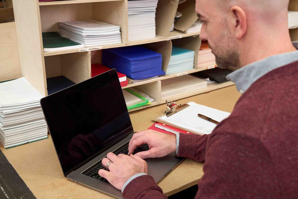 A person seated and in front of a laptop.
