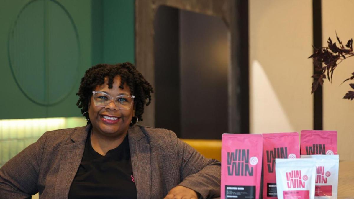 Nikisha Bailey seated next to a display of coffee bags.