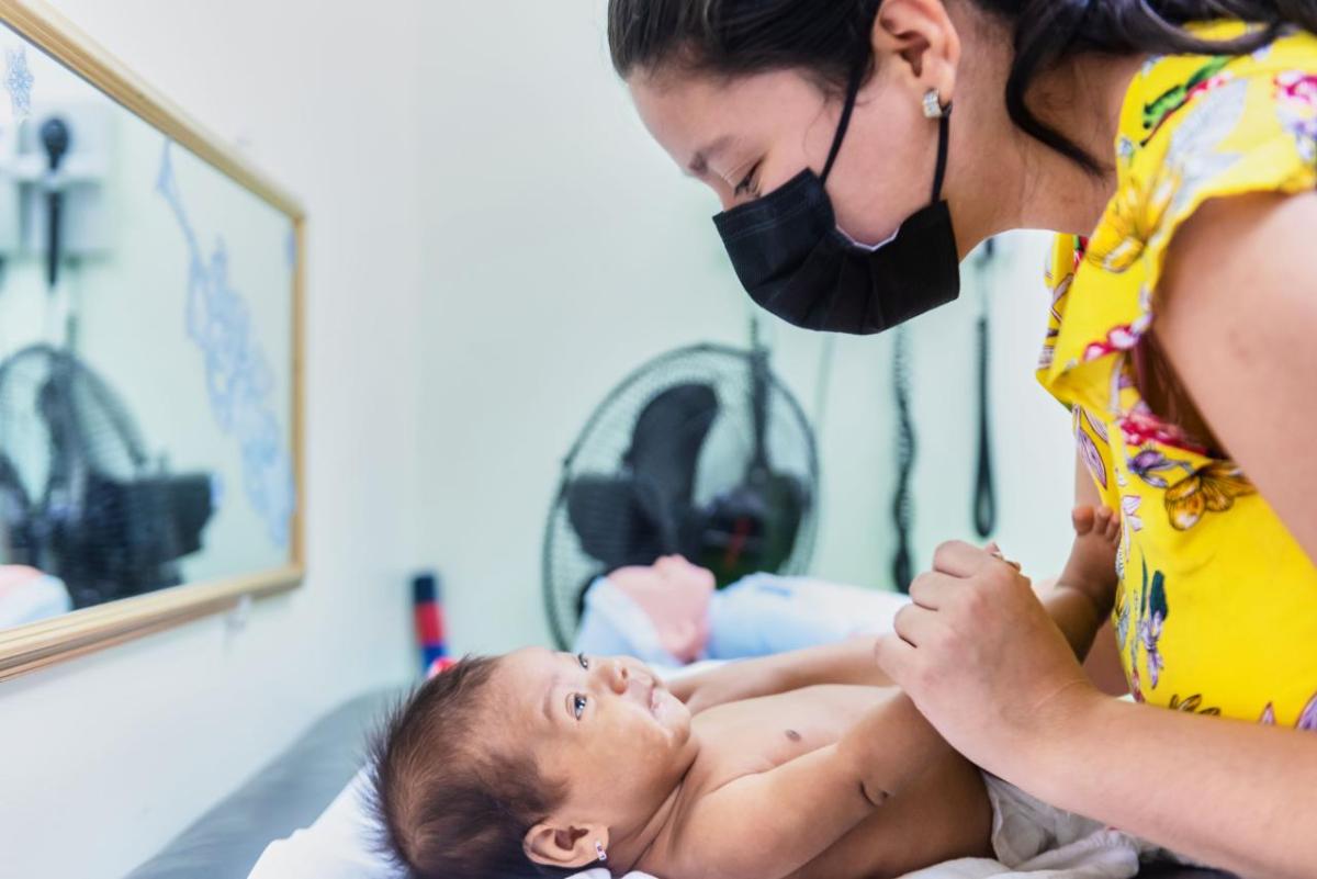 An adult leaning over a baby on a doctor's table.