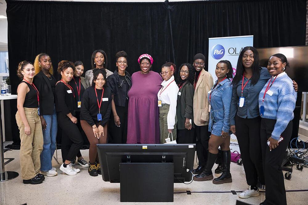 A group of women on a stage with black curtains behind. A floor monitor in front of them