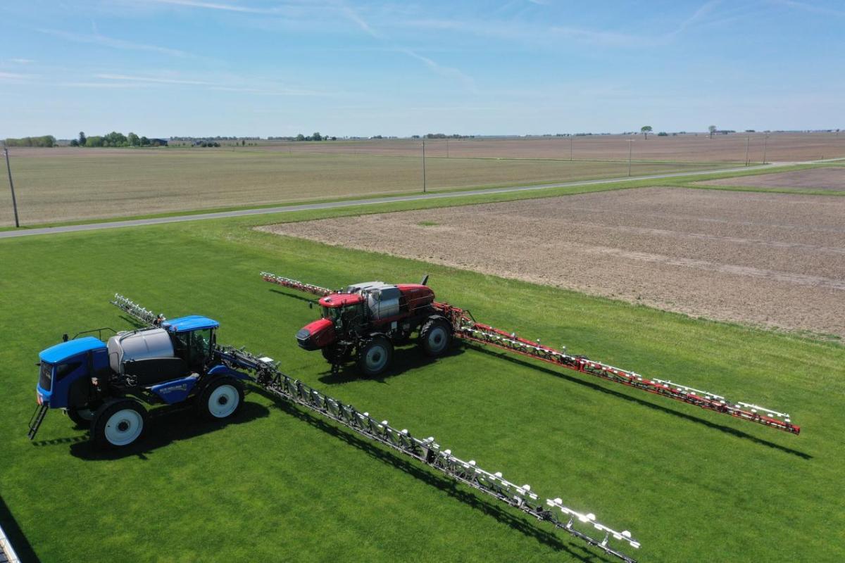 Two tractors spraying fields