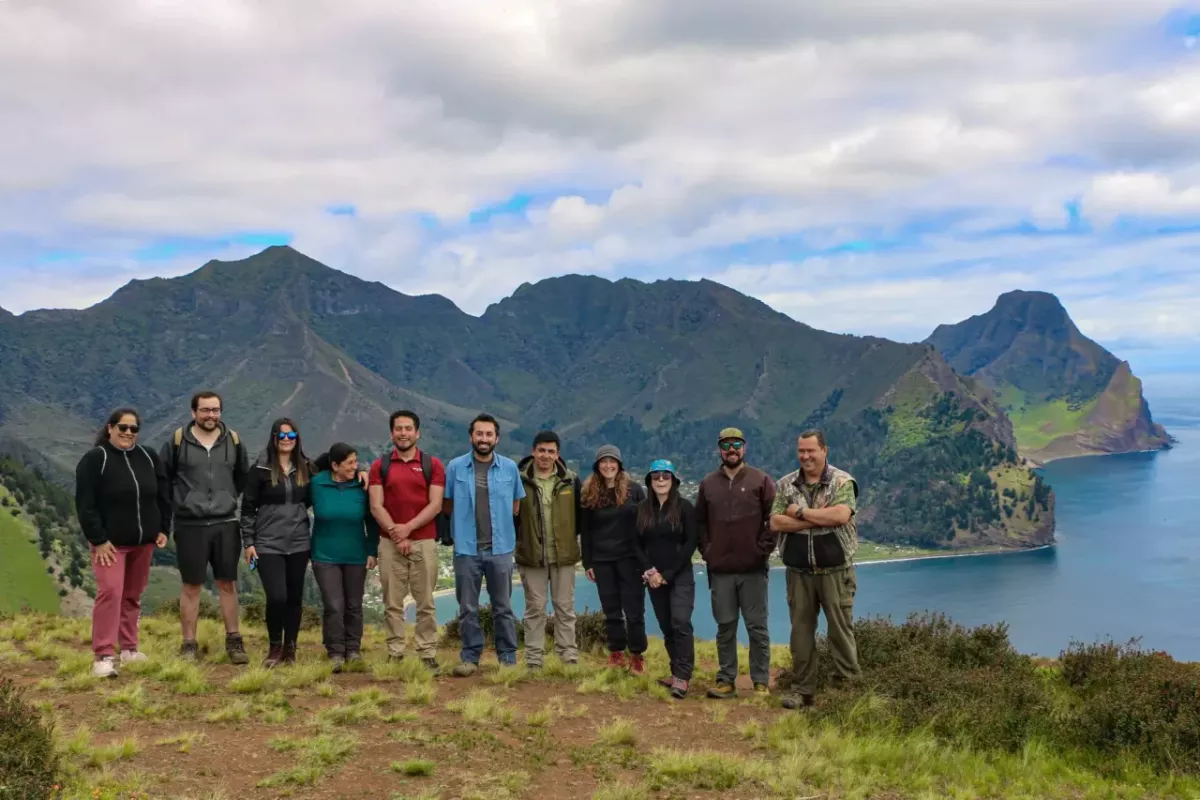 A group of people stood together with mountains in the distance 