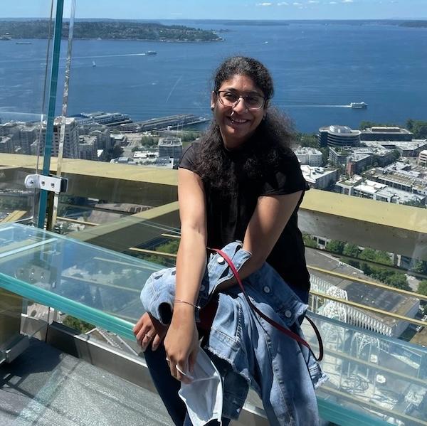 Sanjana seated on an observation deck overlooking a harbor.