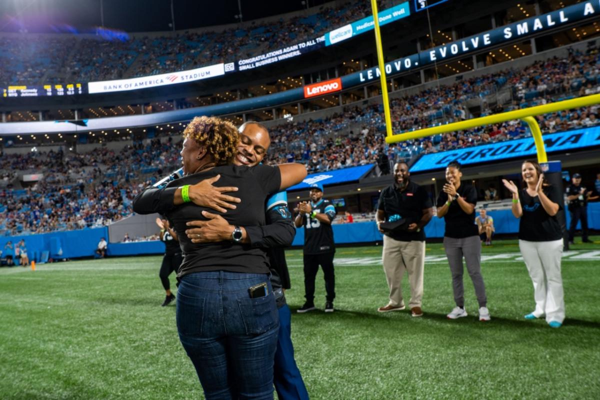 Hip Hop Smoothies of Charlotte representative hugs Lenovo North America CMO Gerald Youngblood on the Carolina Panthers field