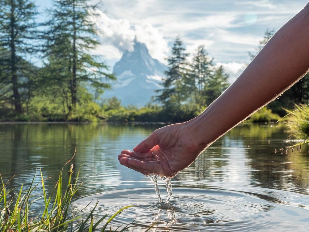 hand scooping water from pond