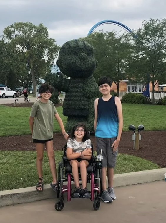 Photo of Alex, Sophia and Maya. Sophia is seated in a wheelchair.
