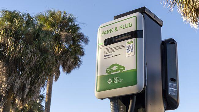 park & plug vehicle charging station close up. Palm trees in the background.