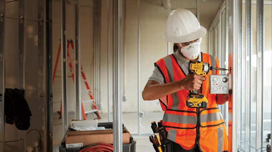 Photo of a trades worker wearing safety equipment while using a handheld tool