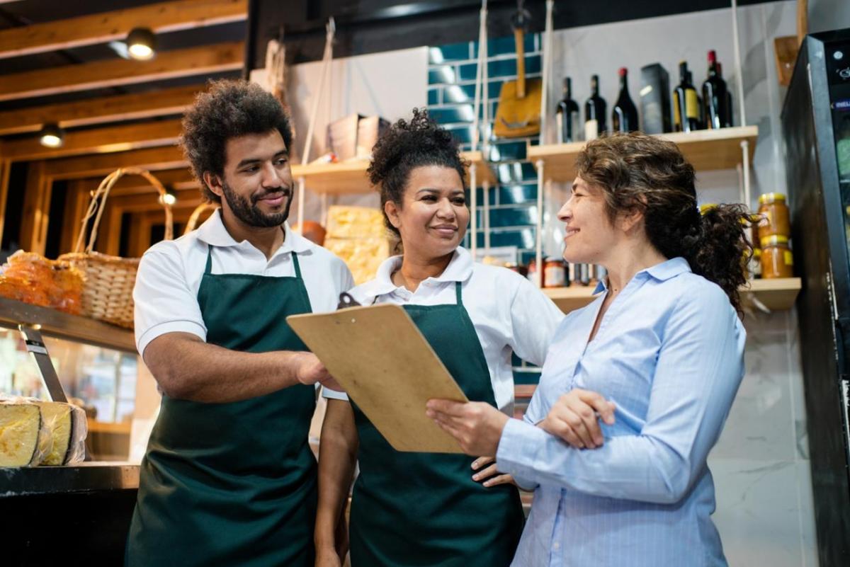 Three retail workers reviewing notes on a clipboard