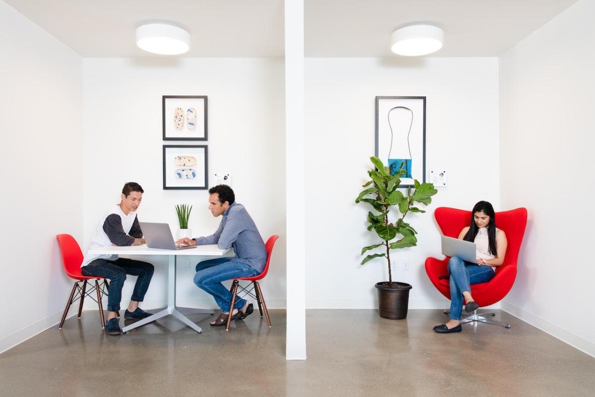 Three people seated and working on laptops.