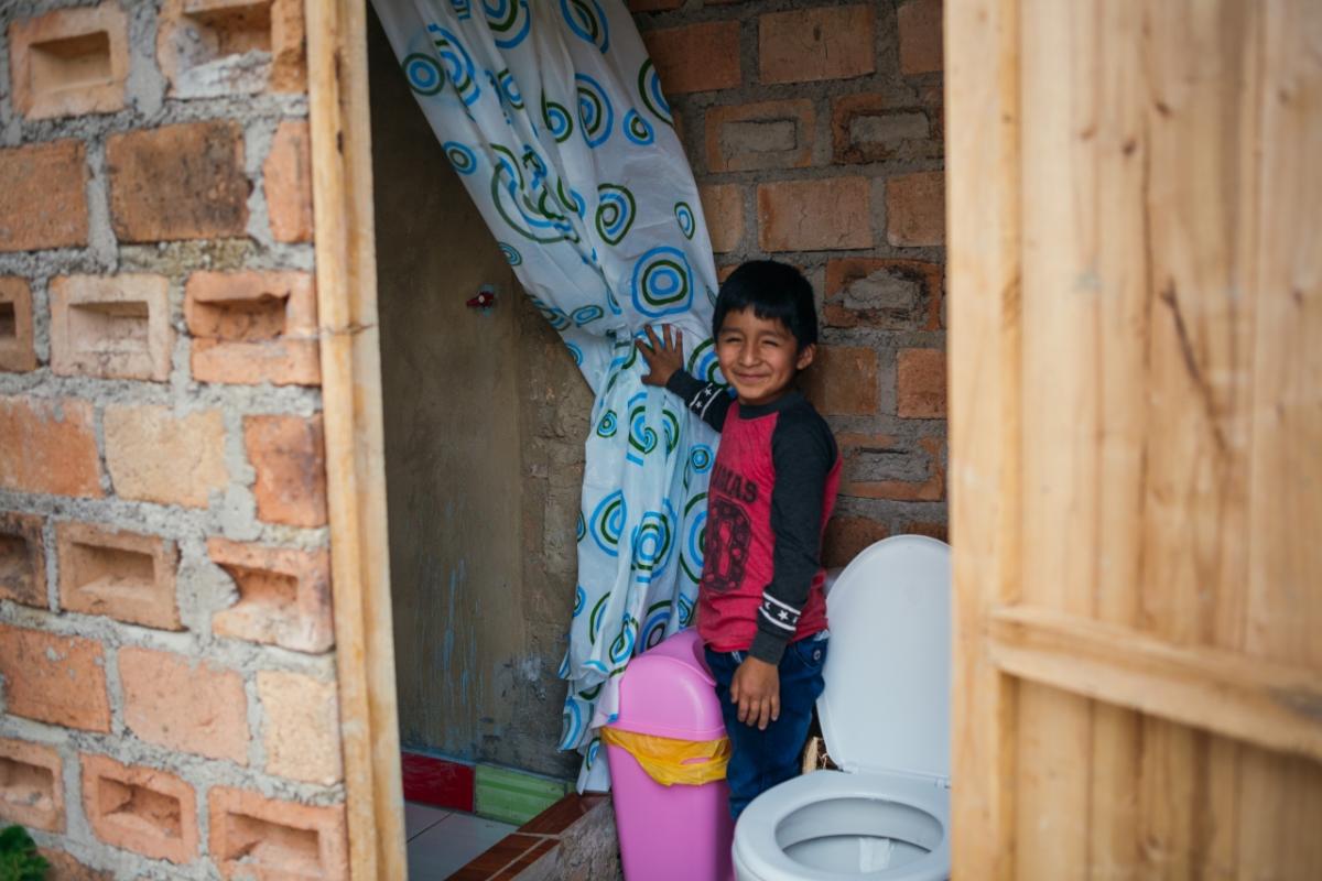Young boy shows his family's new toilet and shower in Peru. 