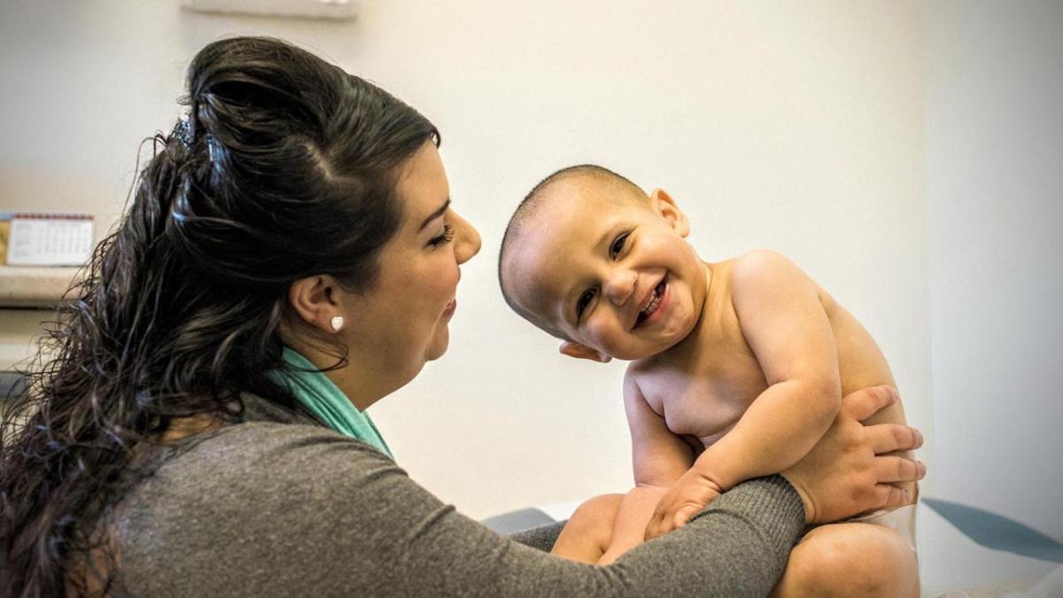 Nineteen U.S. safety-net community healthcare providers were awarded this year for their work supporting innovative approaches to infectious disease treatment. (Photo by Andrew Schoneberger) A woman and an infant smile in a doctor's office at a community health center.