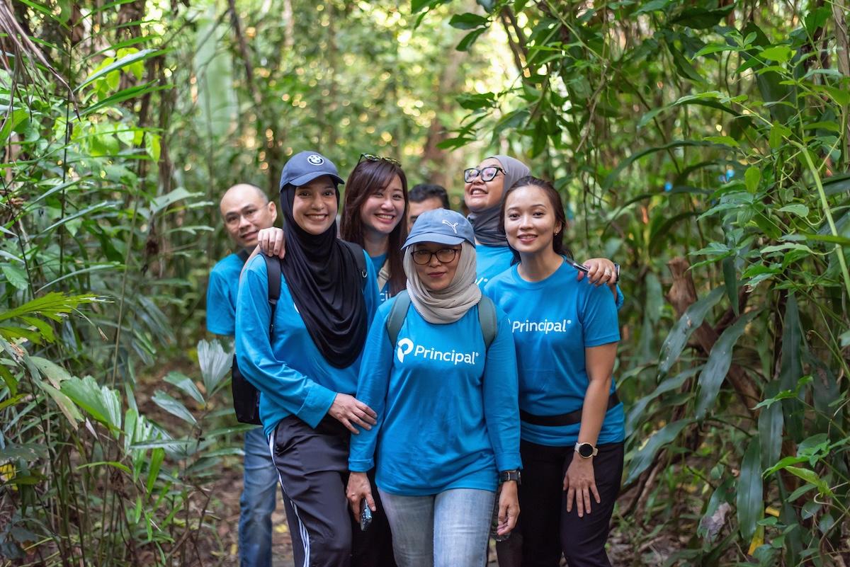 Group of people wearing blue Principal Financial Group shirts in a forest.