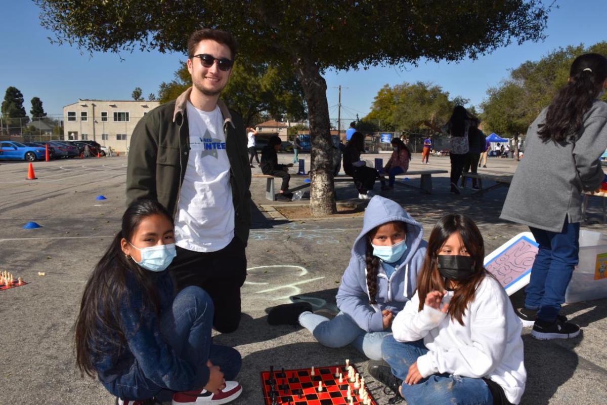 An AEG employee volunteer plays chess with students.