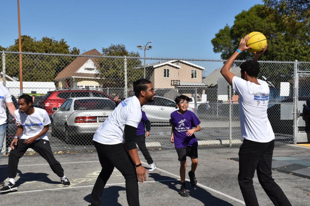 AEG employee volunteers play basketball with students.