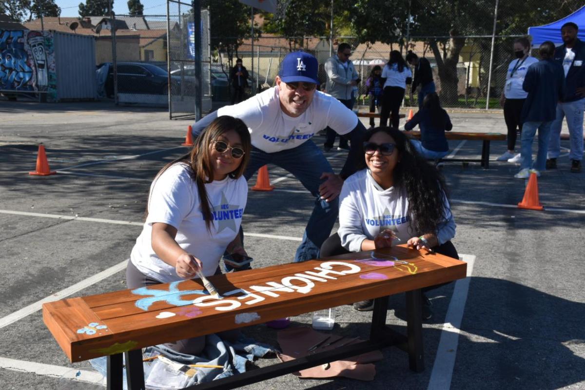 AEG employee volunteers paint a bench.