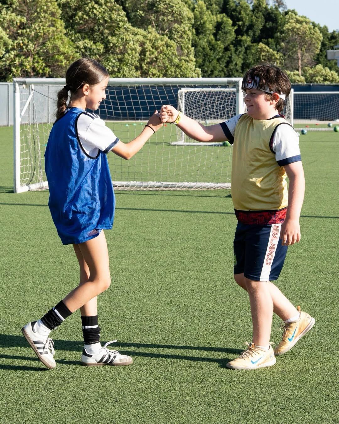 Kids in soccer pinnies fist bumping at Galaxy Park