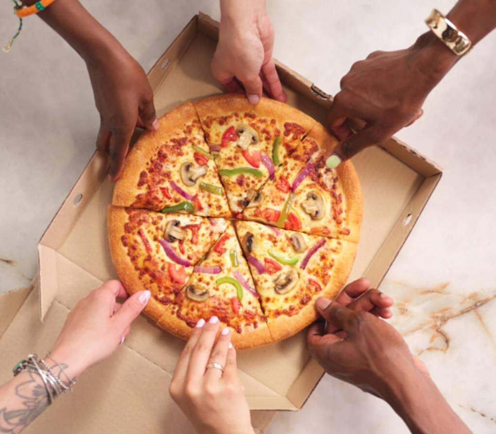 People grabbing a slice of pizza from a box