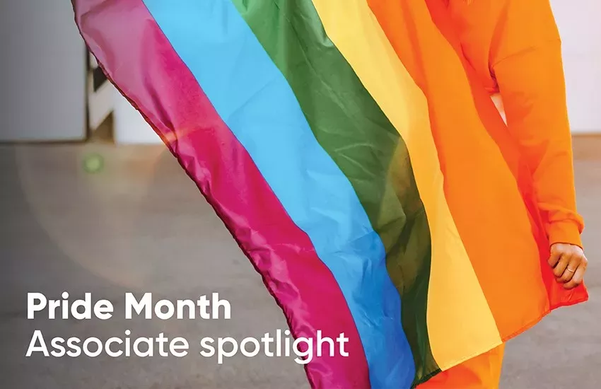 A person holding a rainbow flag. "Pride Month Associate spotlight"