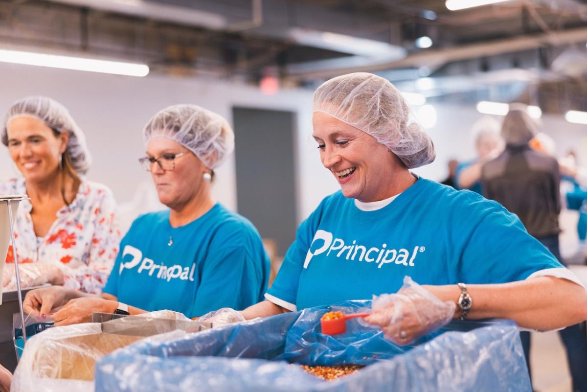 Principal volunteers pack meals to fight child hunger through Meals for the Heartland. " "