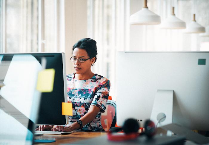 Woman seated at her desk behind a computer monitor.