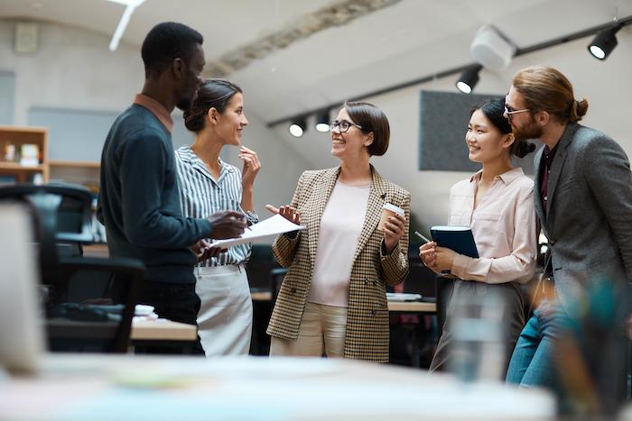 Group of five women and men at work having a discussion.