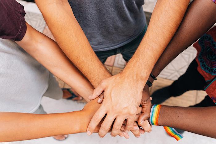 Group of black and white hands joined in the center of a circle.