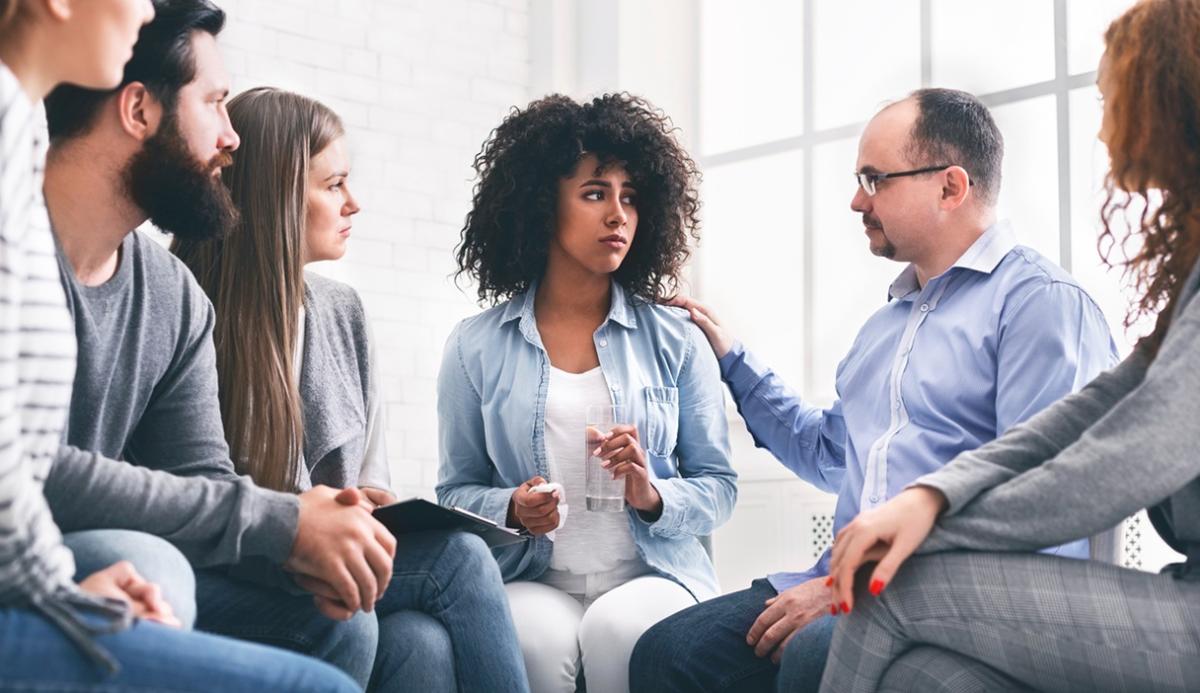 Group of employees supporting a distressed woman in the center