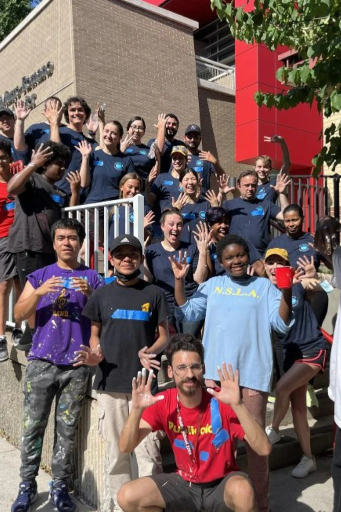 Large group of Publicolor volunteers standing outside of a school