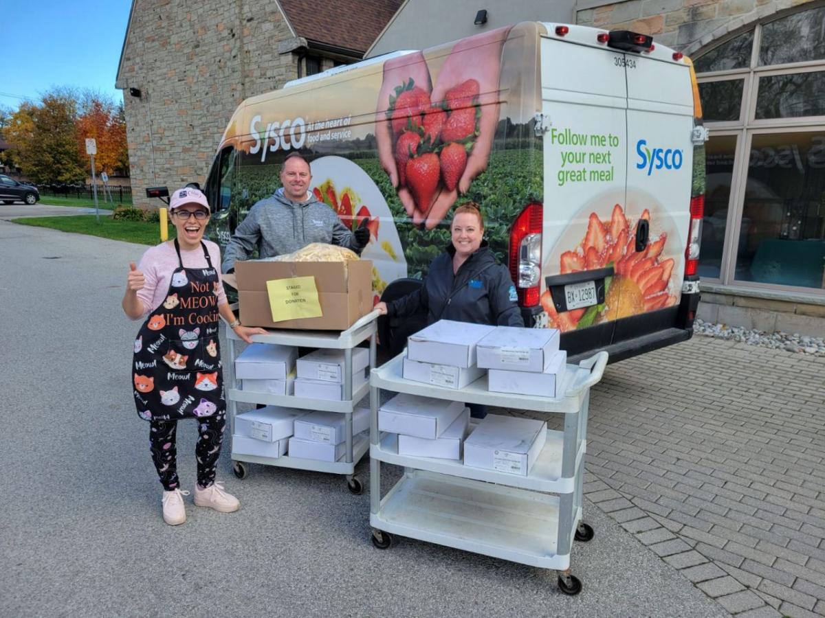 Three people delivering food from a Sysco truck