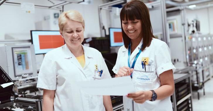 Two female technicians shown reading a report in the HARMAN labs.