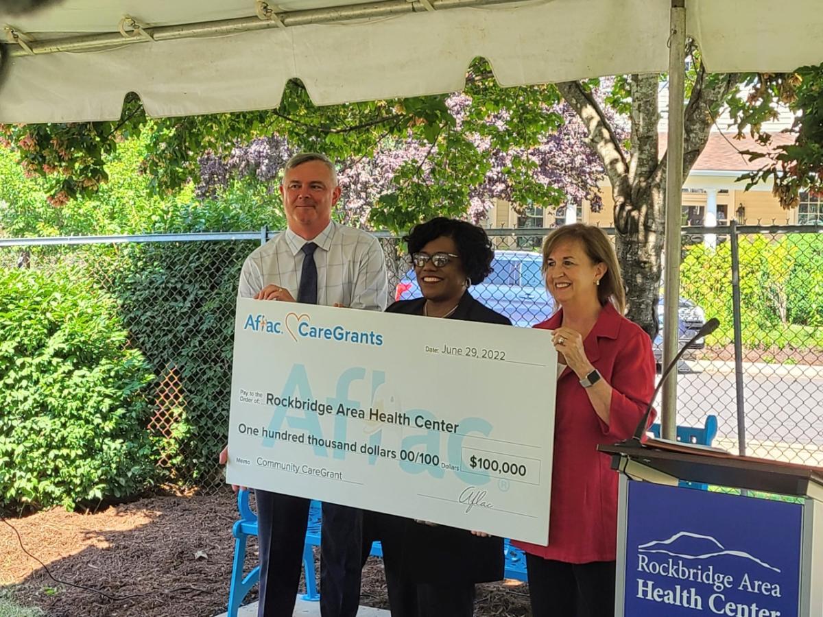 Three people holding a check at the presentation event 