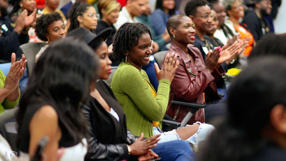 A seated audience clapping and smiling.