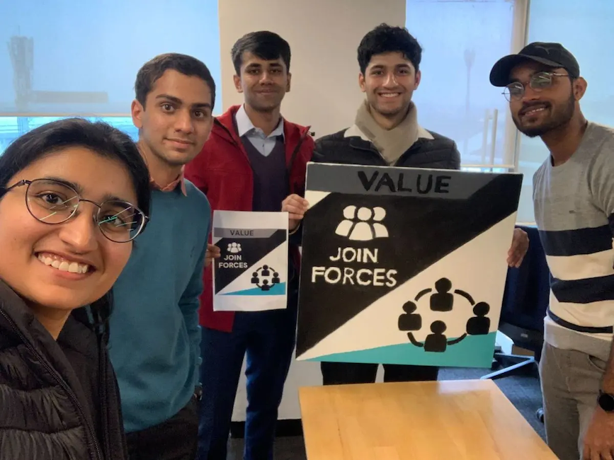 Rahul with friends holding a sign that says: value, join forces.