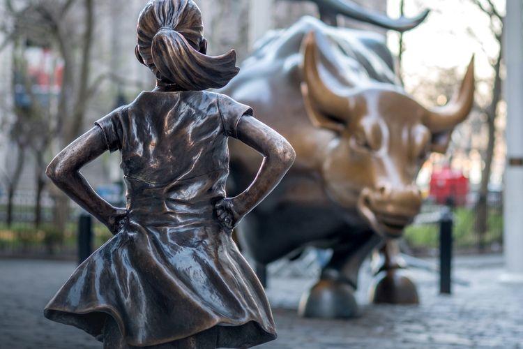 Statues of girl facing a bull