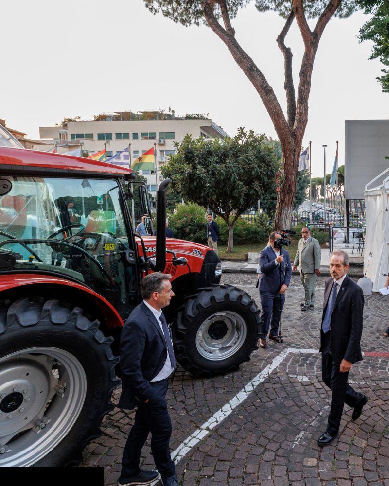 Red tractor parked outside with people walking past 