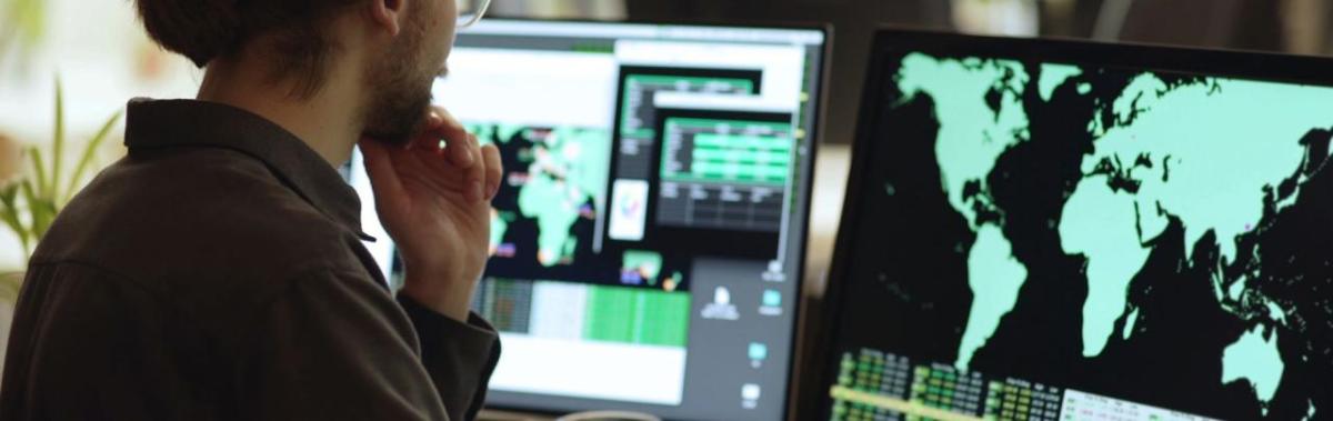 Side angle of someone looking at a computer screens featuring maps