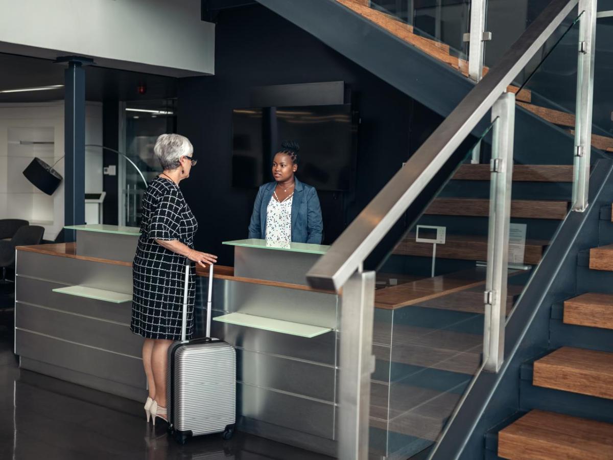 A person checking in at a hotel desk, a staircase to the right.
