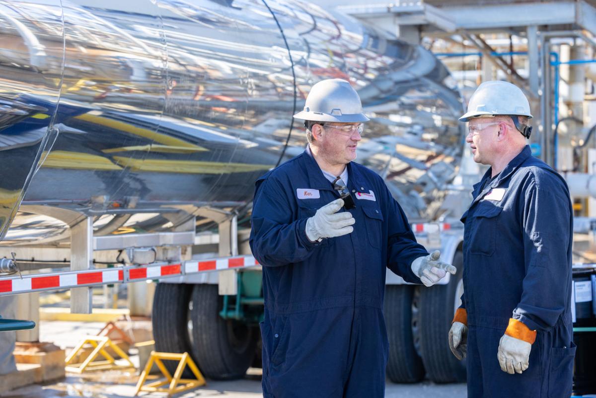 2 workers with hardhats talk outside a truck