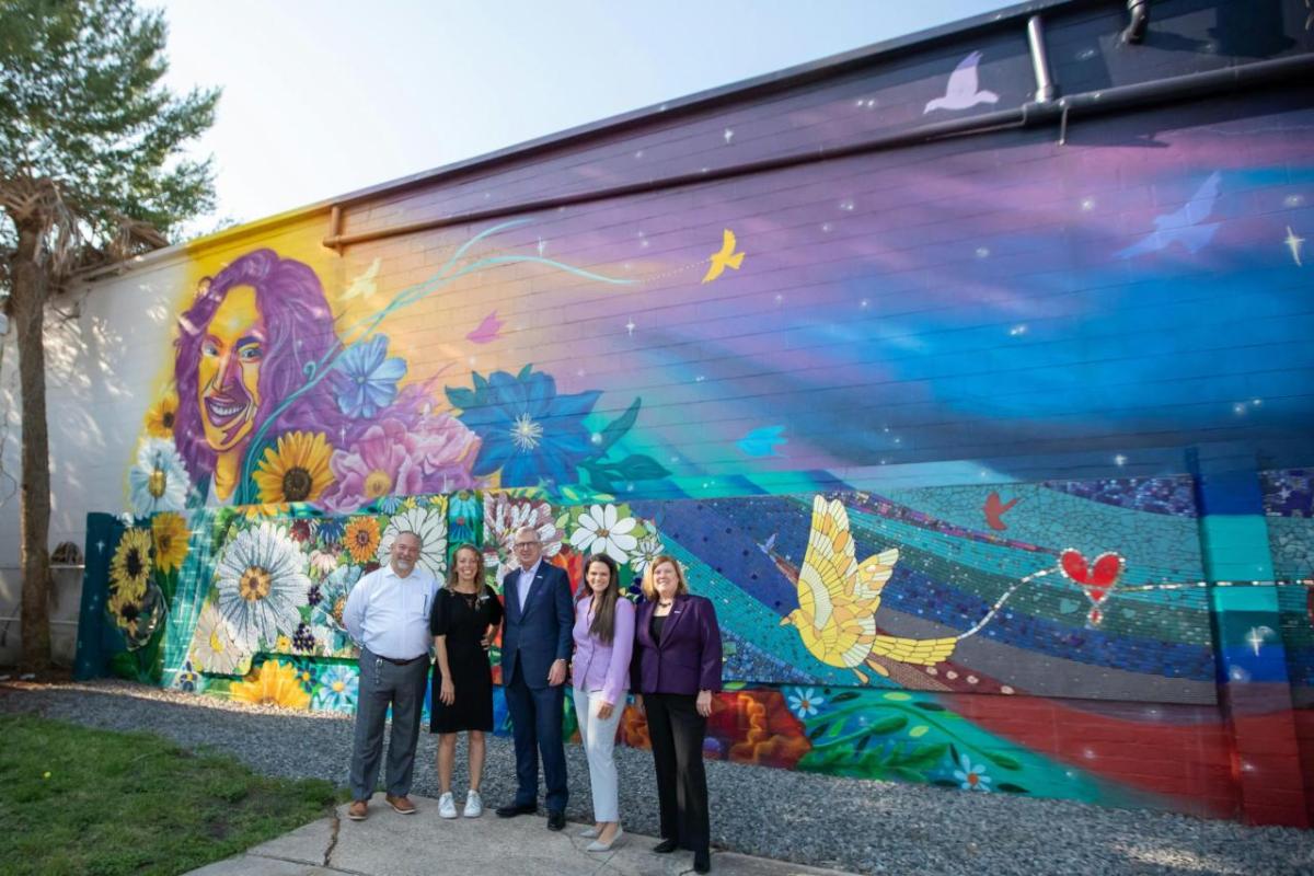 Group of people stood in front of a brick wall which has art on 