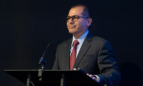 Reymundo at a podium with a microphone, black background