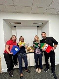 Four people stood together holding Supplies to help children and families 