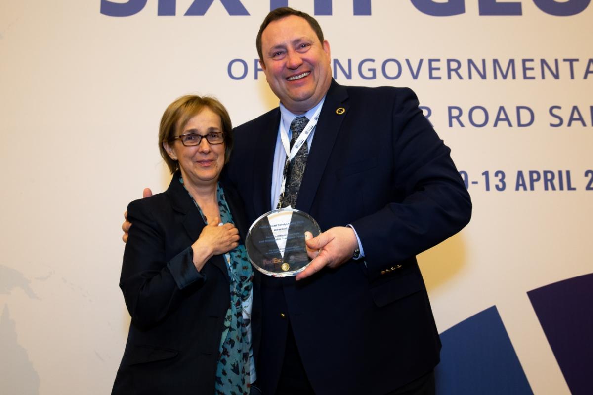 A man and woman posing with an award