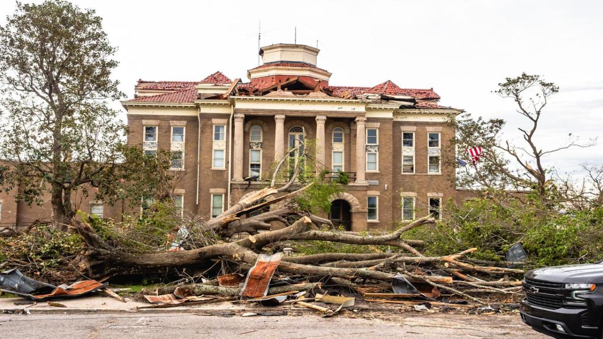 Rolling Fork courthouse with extensive tornado damage. Trees and debris cover the ground.