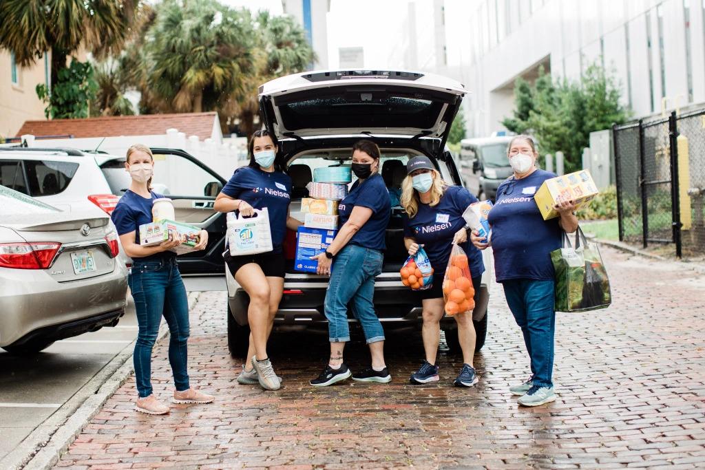 A group of people loading groceries into a car trunk