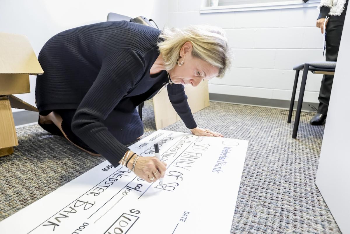 Grant check for $100,00.00 being made out by a representative from Webster Bank.