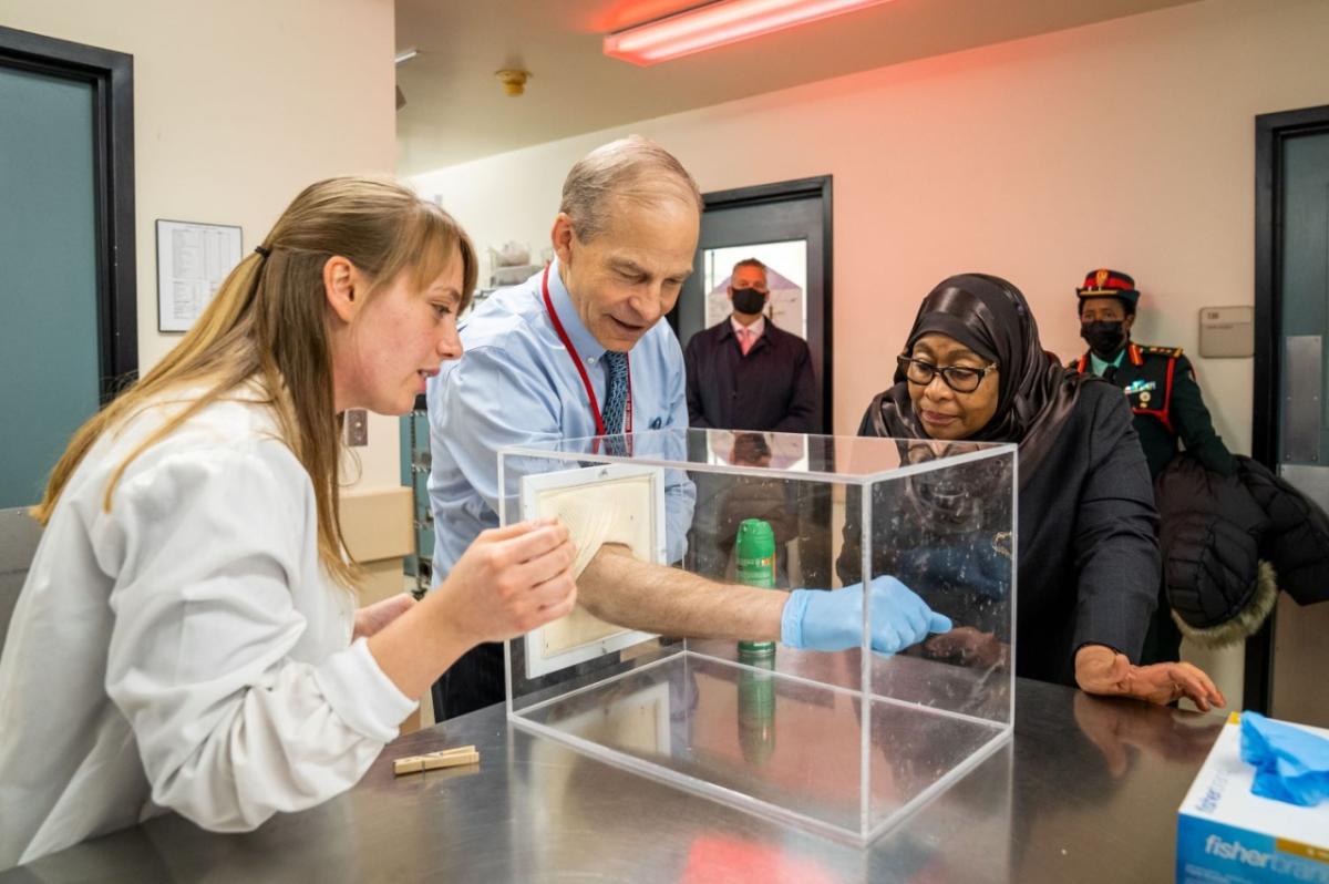 President Hassan of Tanzania observes Fisk Johnson, Chairman and CEO of SC Johnson, testing the efficacy of OFF! ® insect repellent at SC Johnson’s Center for Insect Science and Family Health. three people standing over glass box