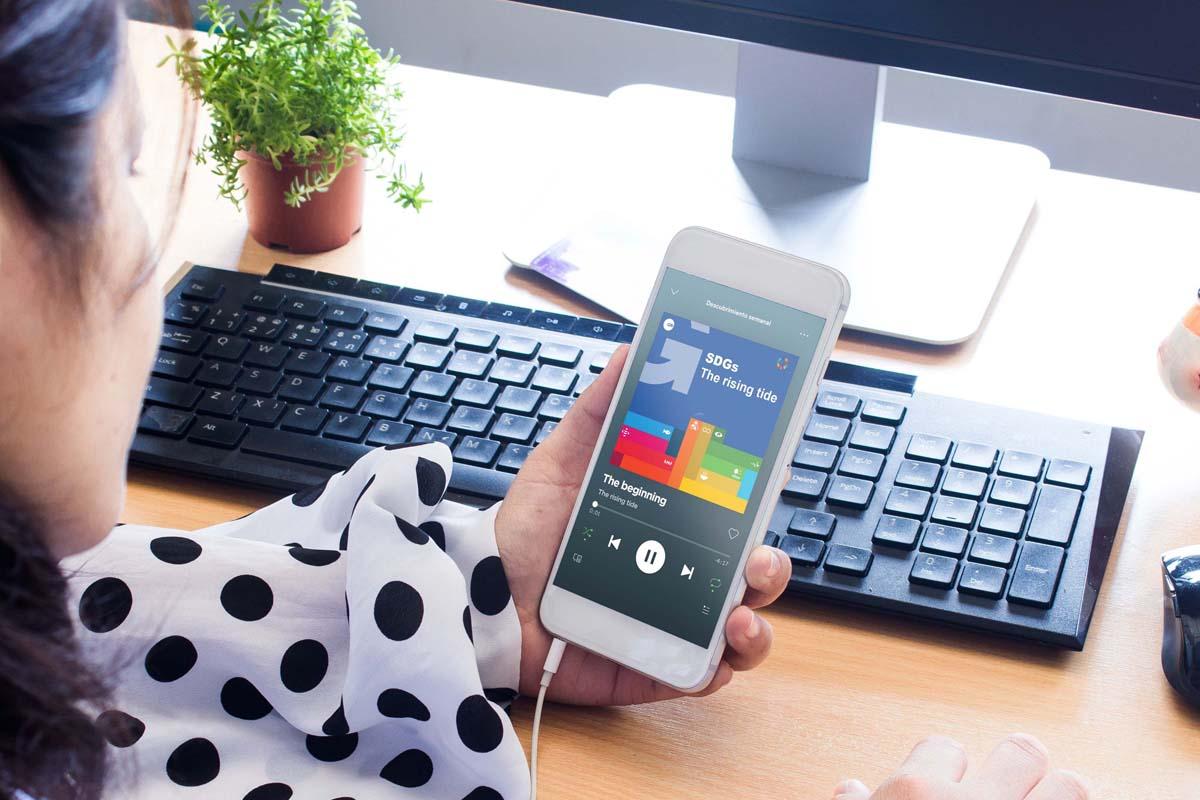 The Rising Tide - podcast series on SDGs reporting from GRI person looking at smartphone